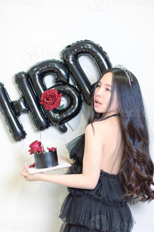 bellissimo donna indossare un' nero vestito e cioccolato torta nel il concetto di compleanno foto