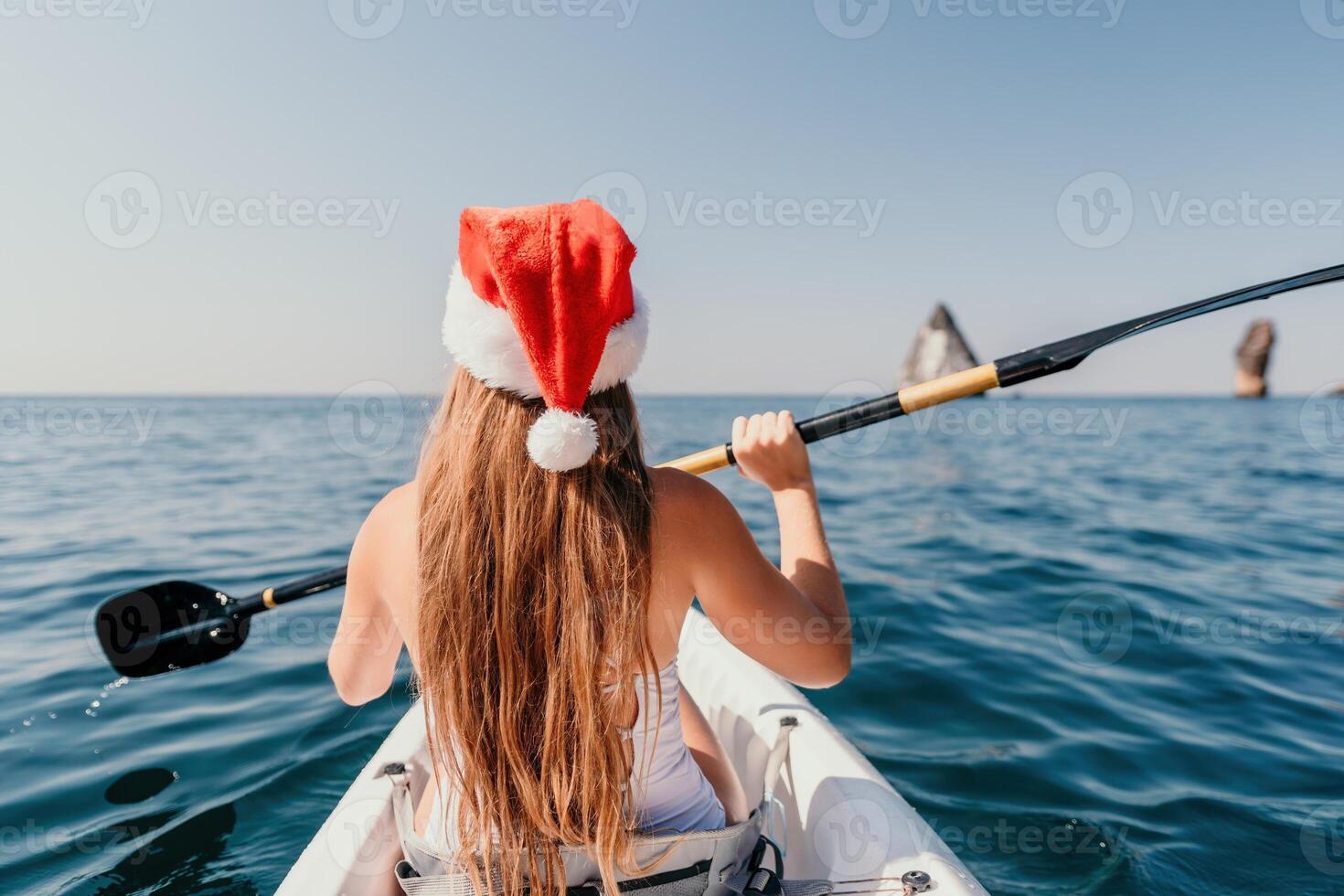 donna nel kayak indietro Visualizza. contento giovane donna nel Santa cappello galleggiante nel kayak su calma mare. estate vacanza vacanza e allegro femmina persone rilassante avendo divertimento su il barca. foto