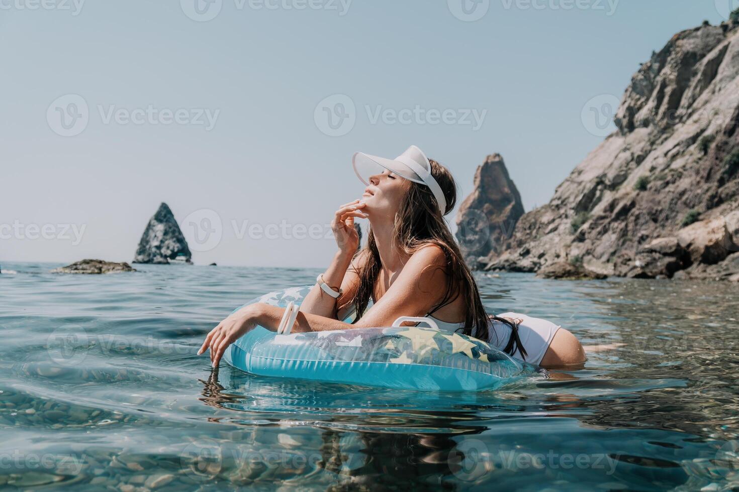 donna estate mare. contento donna nuoto con gonfiabile ciambella su il spiaggia nel estate soleggiato giorno, circondato di vulcanico montagne. estate vacanza concetto. foto