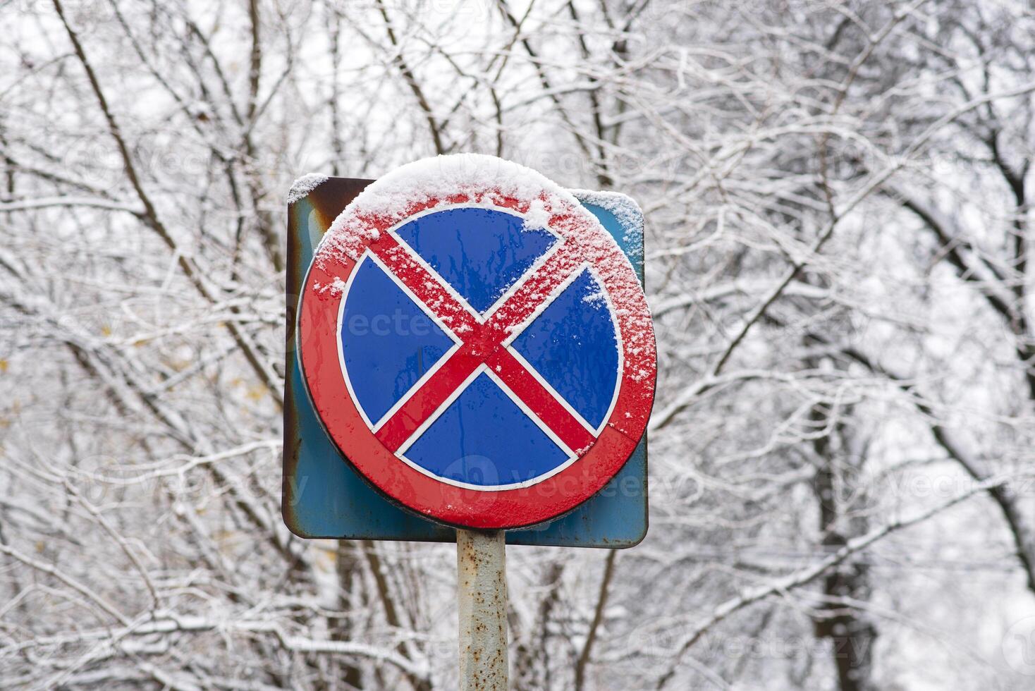 no in piedi o parcheggio strada cartello coperto nel neve. soleggiato inverno giorno. rosso e blu colore. foto