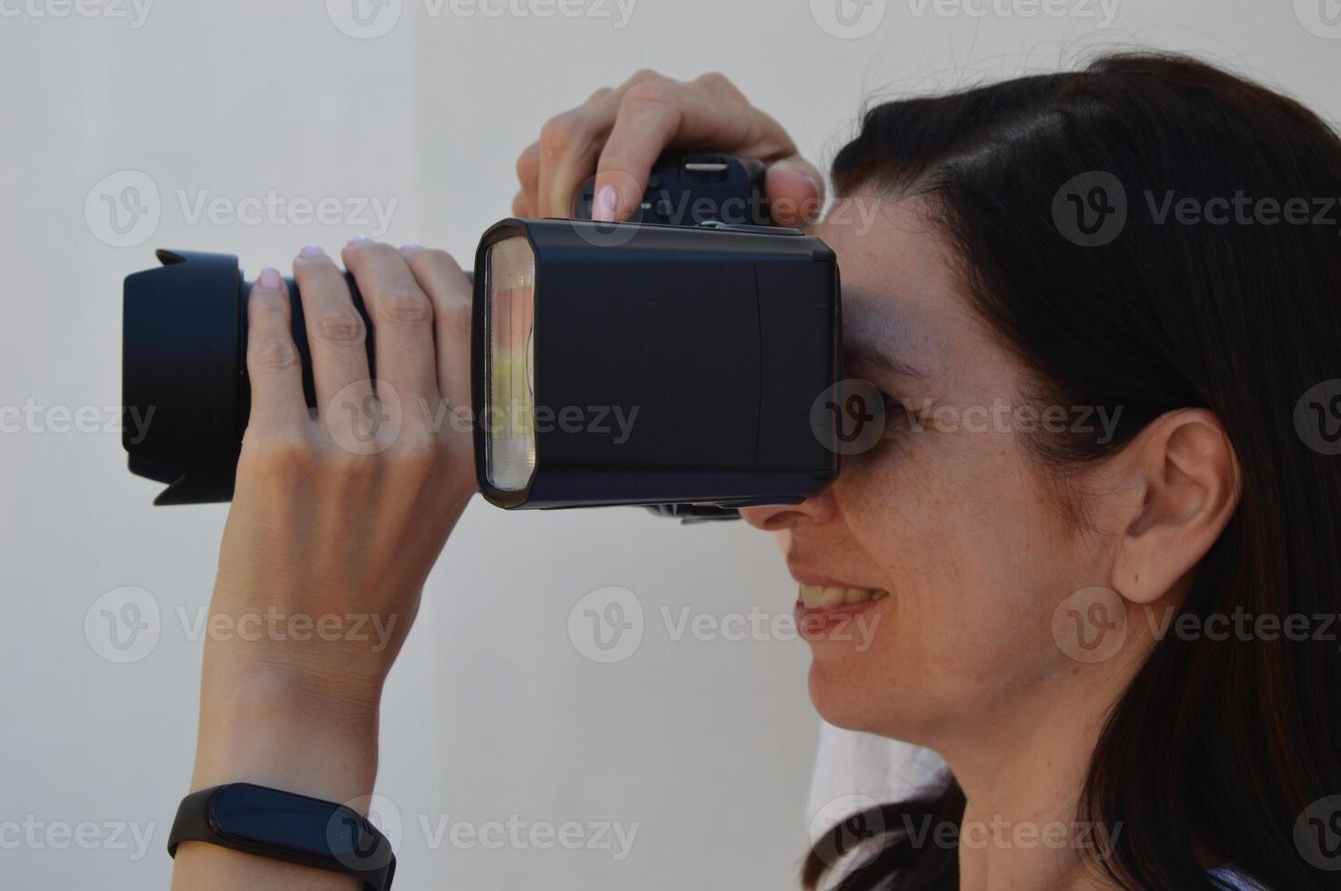 avvicinamento di il tiro processi. donna fotografo con un' telecamera nel sua mani. foto