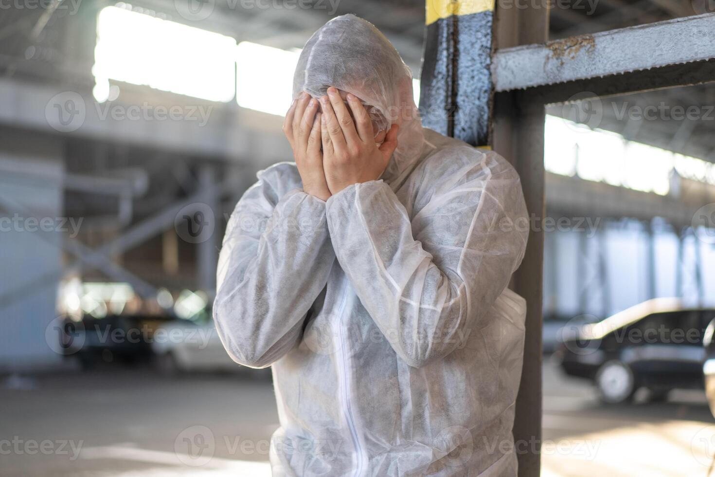 disperazione assistenza sanitaria lavoratore nel bianca covid protettivo tuta da lavoro. stanco maschio caucasico medico afferra il suo testa rannicchiarsi nel depressione durante coronavirus pandemia foto