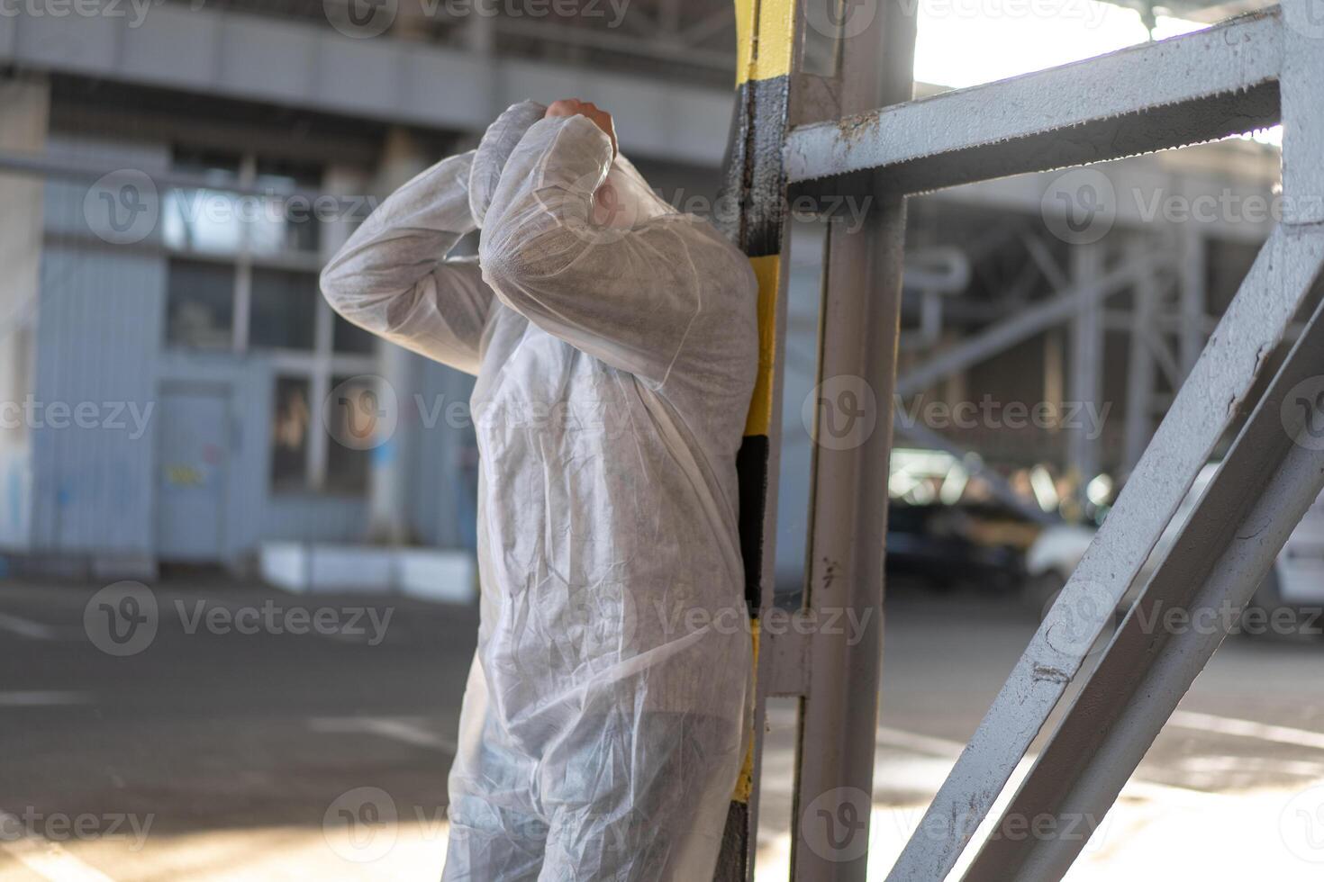 disperazione assistenza sanitaria lavoratore nel bianca covid protettivo tuta da lavoro. stanco maschio caucasico medico afferra il suo testa rannicchiarsi nel depressione durante coronavirus pandemia foto