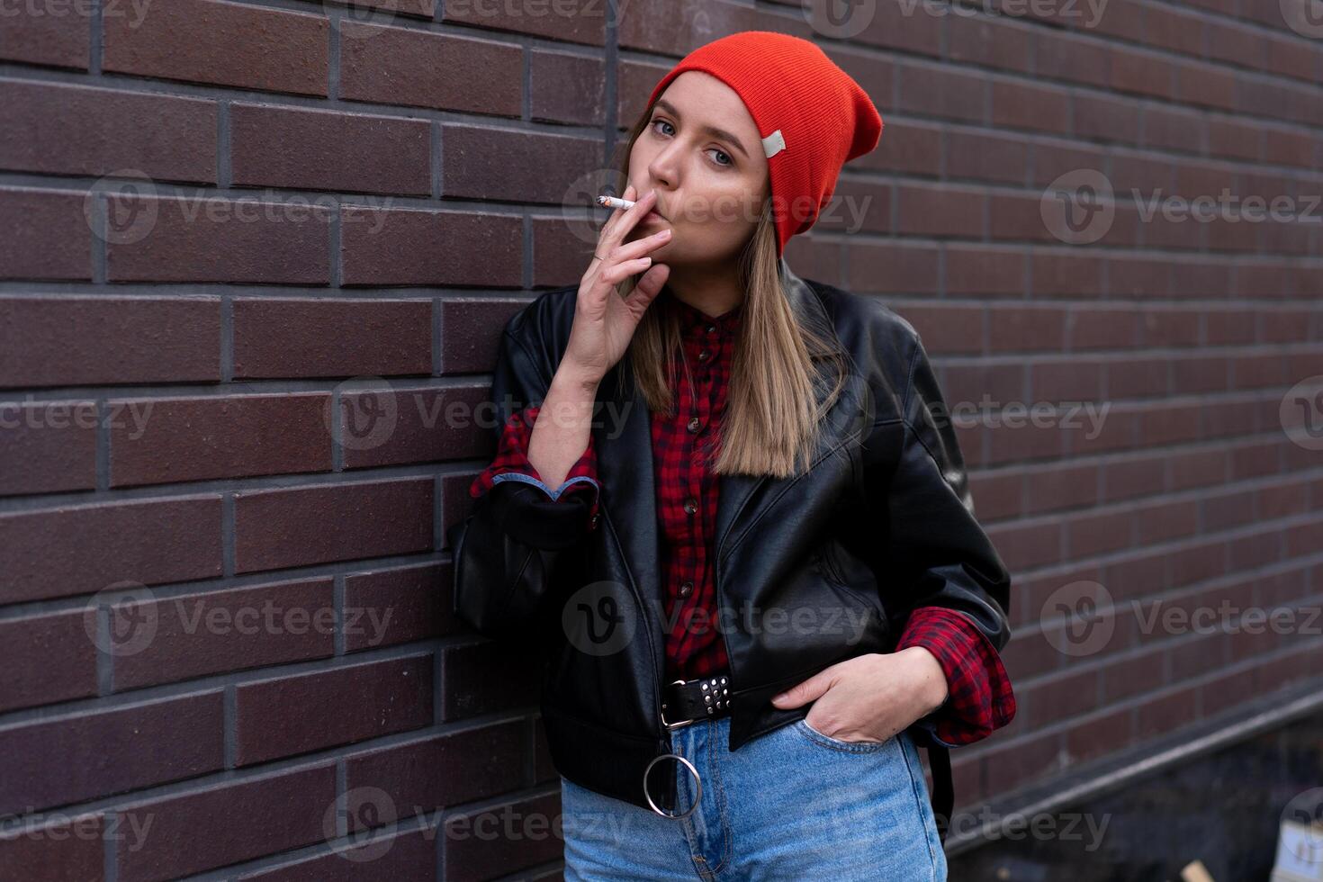 bellissimo giovane con stile vestito caucasico ragazza fuma sigaretta su il strada. foto