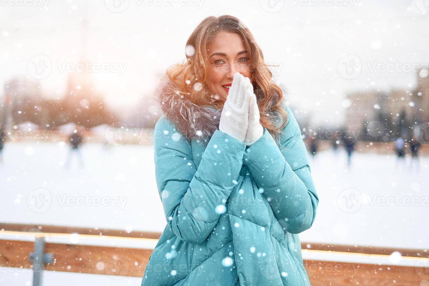 bellissimo bello di mezza età ragazza con Riccio capelli caldo inverno giacche sta ghiaccio pista sfondo cittadina quadrato. foto