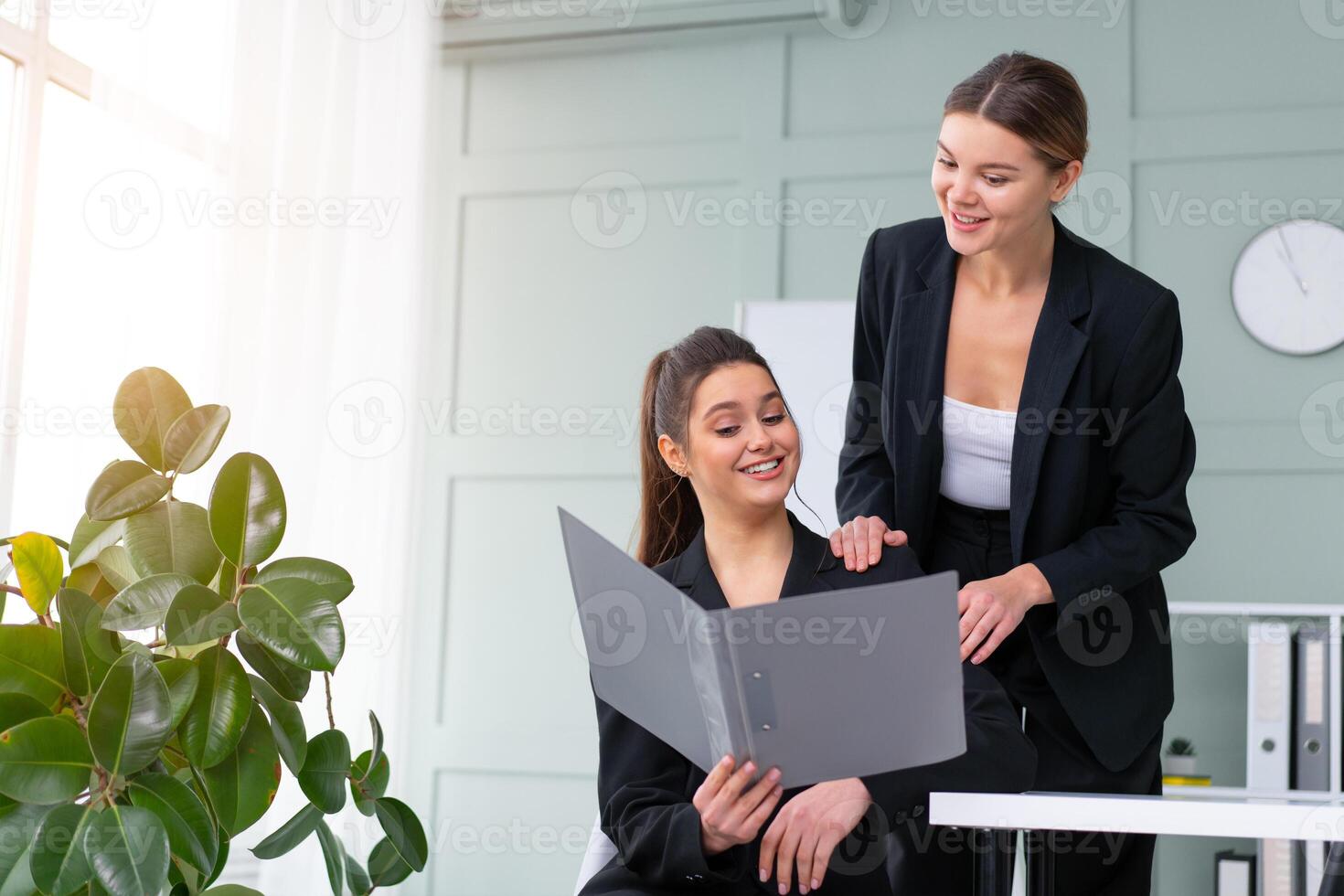 giovane donne capi siamo controllo finanziario dichiarazioni a partire dal carta documenti. Due femmina fiducioso attività commerciale lavoratore vestito nero completo da uomo nel ufficio controllo finanziario documento foto