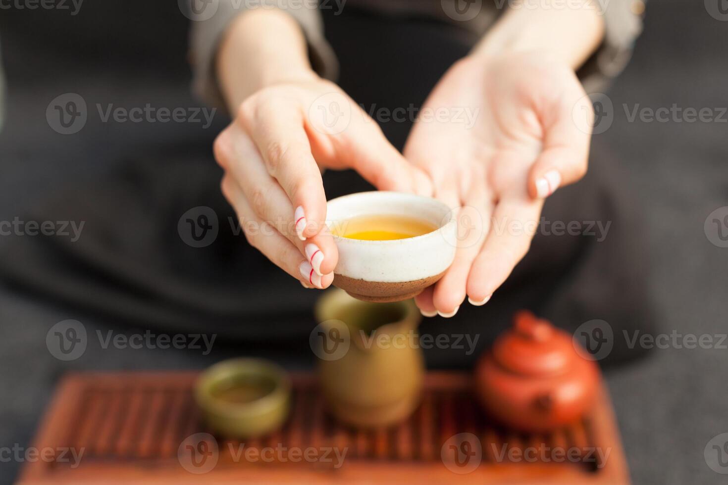 un' ragazza nel un' grigio biancheria camicia organizza un' reale cerimonia, classico Accessori per un' tè cerimonia. concetto di salutare cibo e tradizionale bevande foto