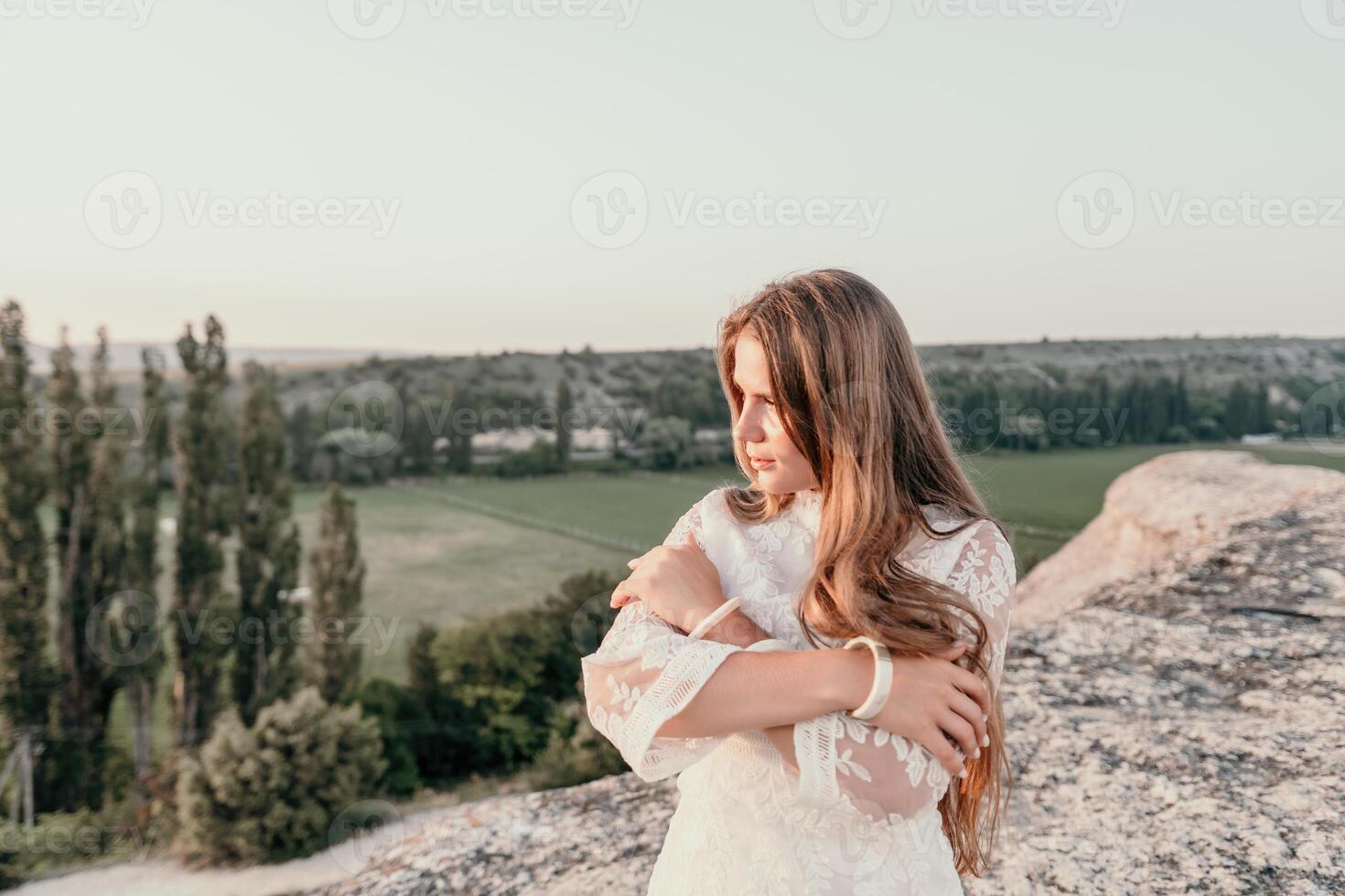 contento donna nel bianca boho vestito su tramonto nel montagne. romantico donna con lungo capelli in piedi con sua indietro su il tramonto nel natura nel estate con Aperto mani. silhouette. natura. tramonto. foto