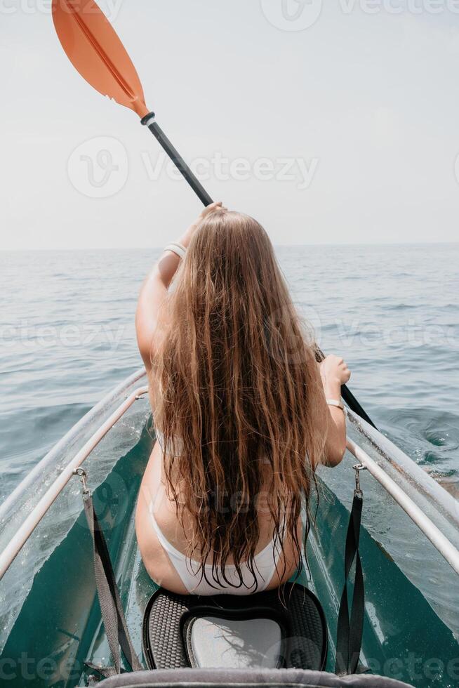 donna nel kayak indietro Visualizza. contento giovane donna con lungo capelli galleggiante nel trasparente kayak su il cristallo chiaro mare. estate vacanza vacanza e allegro femmina persone rilassante avendo divertimento su il barca foto