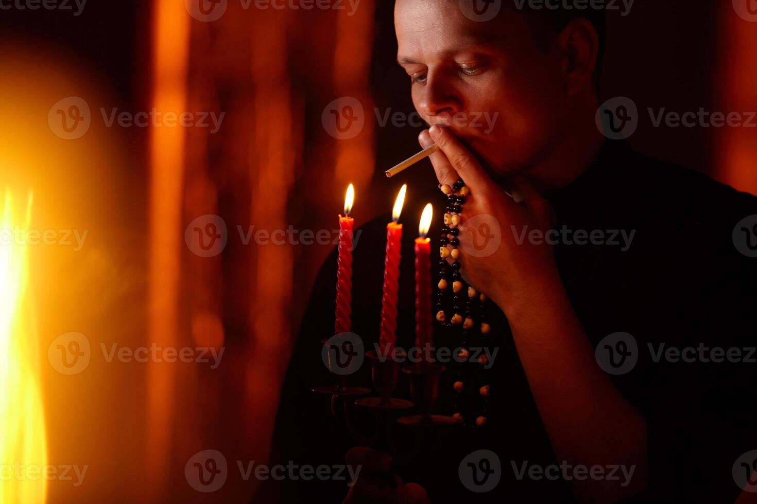giovane adulto caucasico cattolico sacerdote su buio rosso sfondo foto