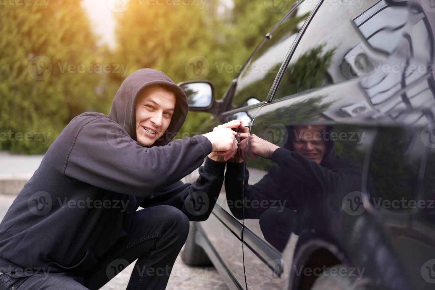 auto ladro rubare auto rottura porta penale lavoro scassinatore dirottamenti auto ladro nero Balaclava felpa con cappuccio provando rompere in veicolo Cacciavite strada crimine violenza gangster rapinatore automobile foto