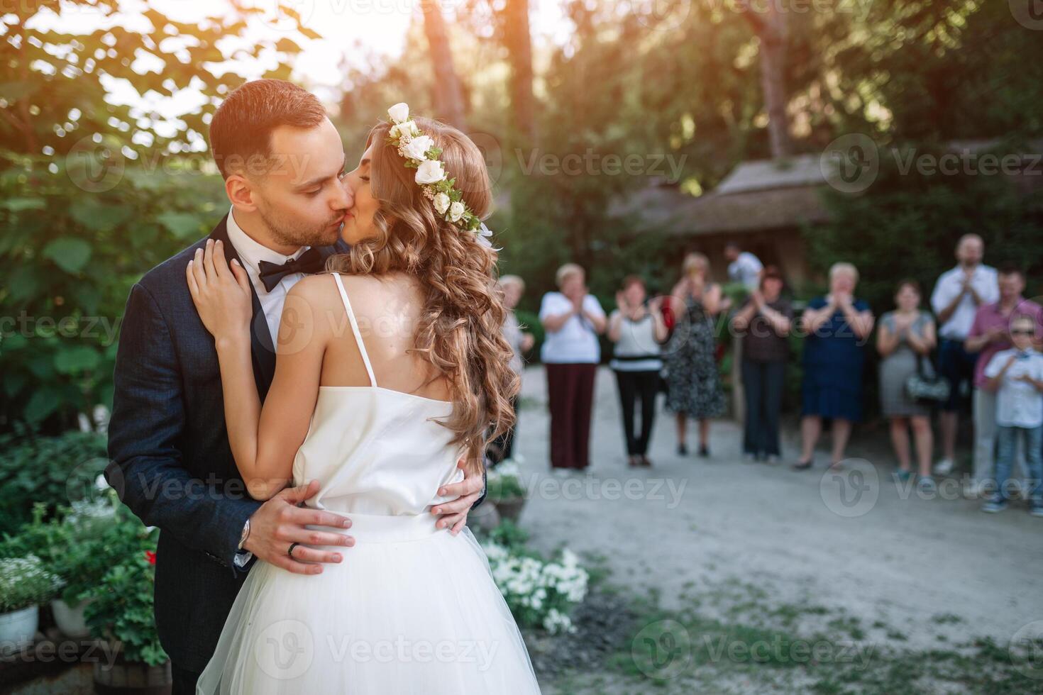 il sposo baci il sposa nel davanti di il ospiti a il Uscita cerimonia foto