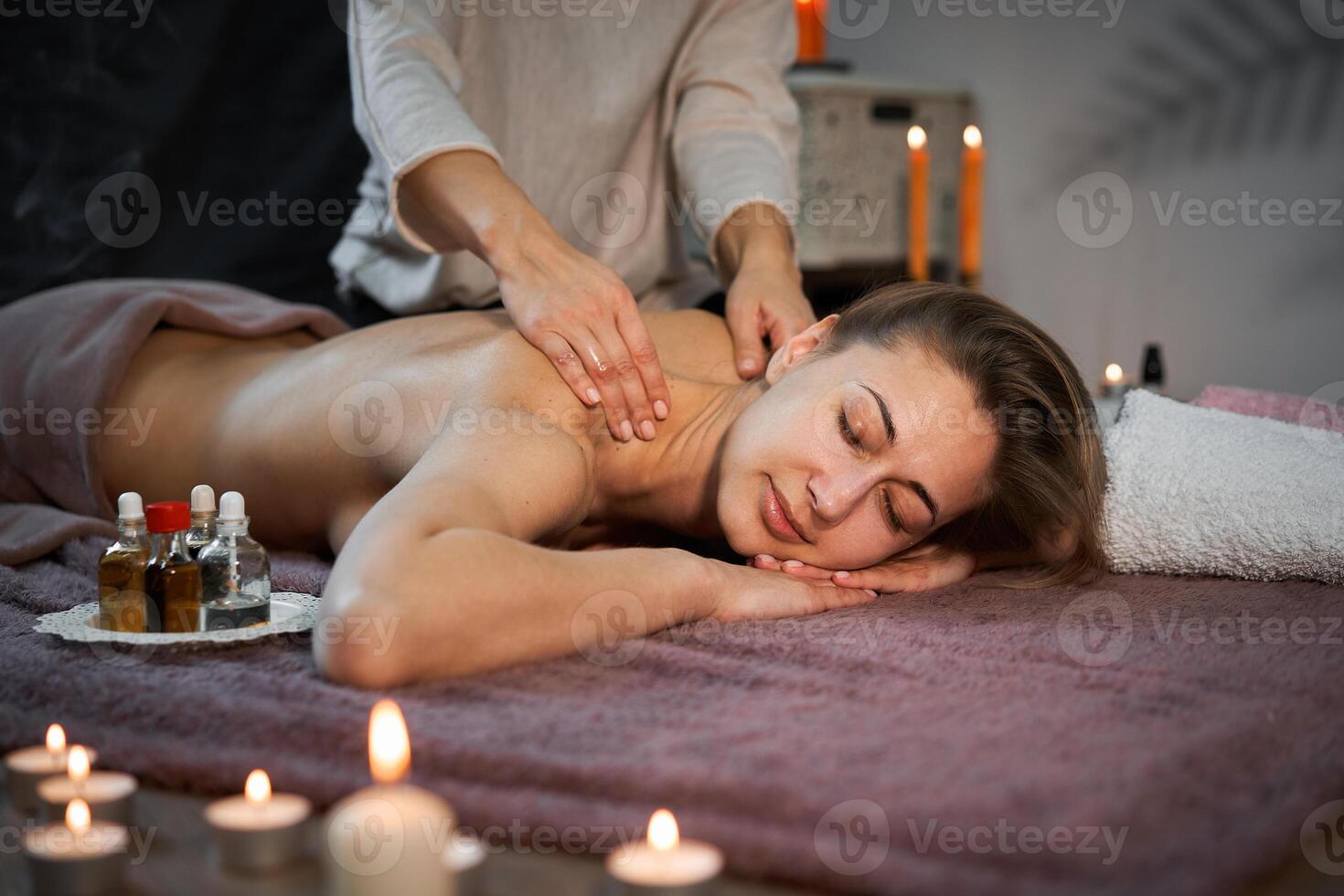 rilassare e godere nel terme salone, ottenere massaggio di professionale massaggiatore. donna dire bugie con nudo indietro rilassare su pavimento coperta foto