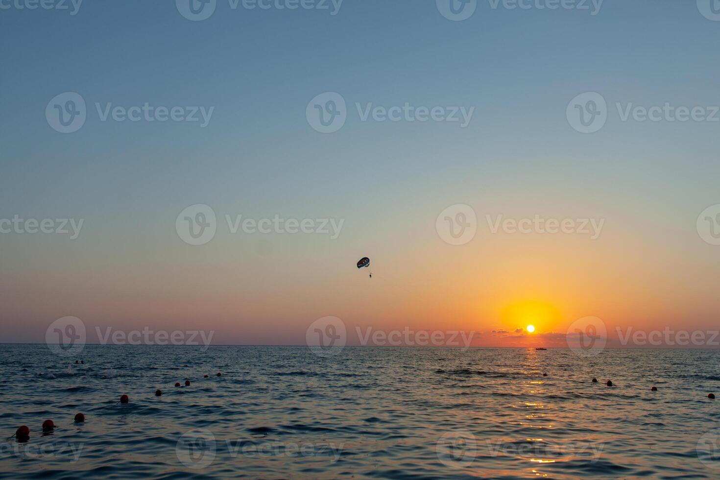 silhouette di motorizzato parapendio Soaring volo al di sopra di il mare contro meravigliosa arancia tramonto cielo. parapendio - ricreativo e competitivo avventura sport. foto