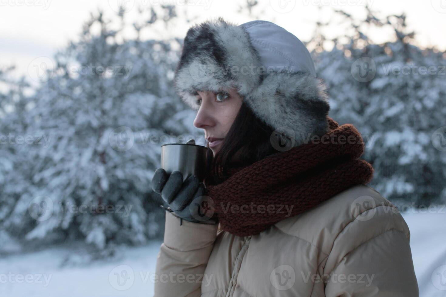 bellissimo ragazza nel un' nevoso inverno foresta potabile caldo tè a partire dal un' thermos foto