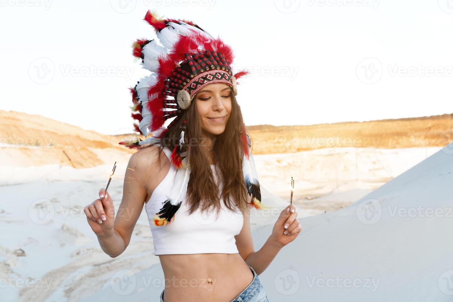 un' bellissimo giovane caucasico ragazza nel un' bianca superiore su sua testa è indossare un indiano cappello. scarafaggio è nel il deserto. contento vacanza umore. foto
