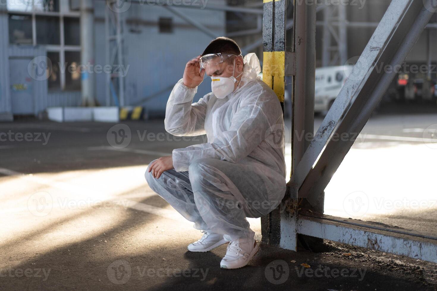 disperazione assistenza sanitaria lavoratore nel bianca covid protettivo tuta da lavoro. stanco maschio caucasico medico afferra il suo testa rannicchiarsi nel depressione durante coronavirus pandemia foto