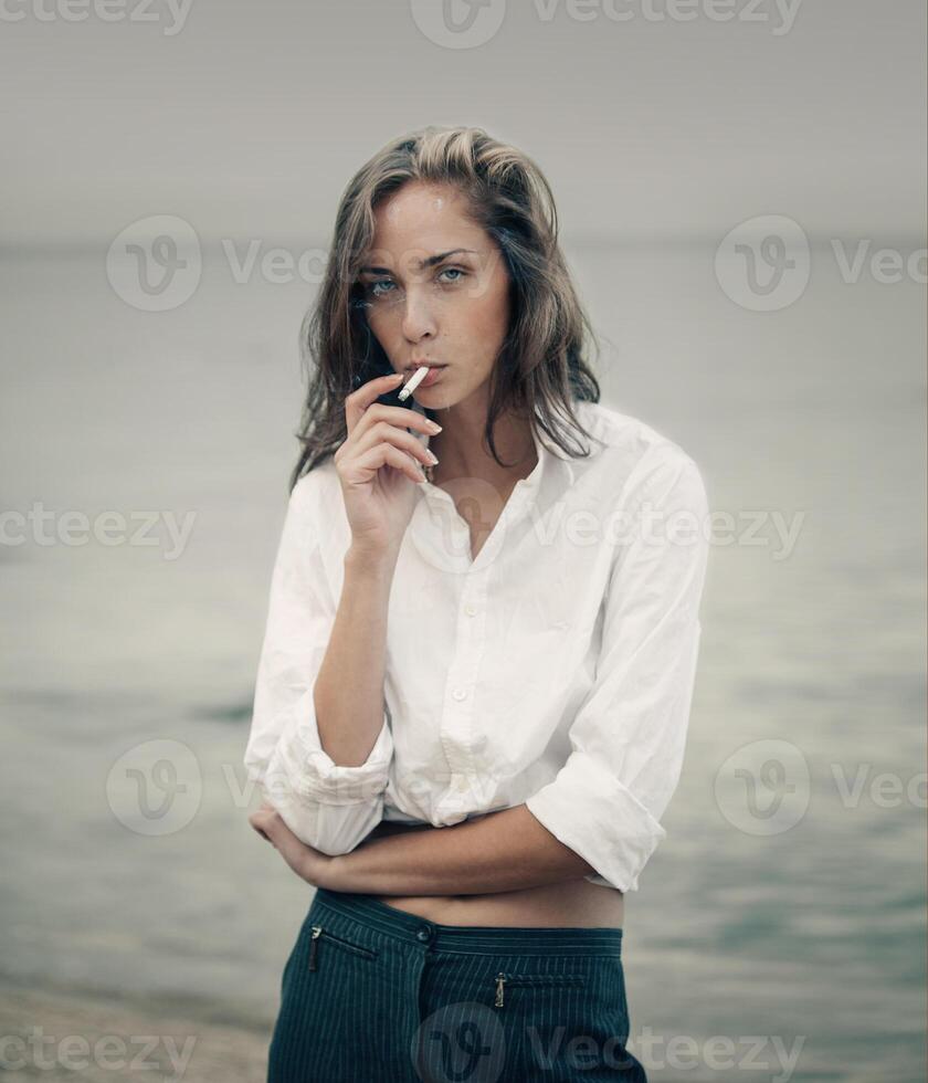 carino donna fuma un' sigaretta su il spiaggia foto