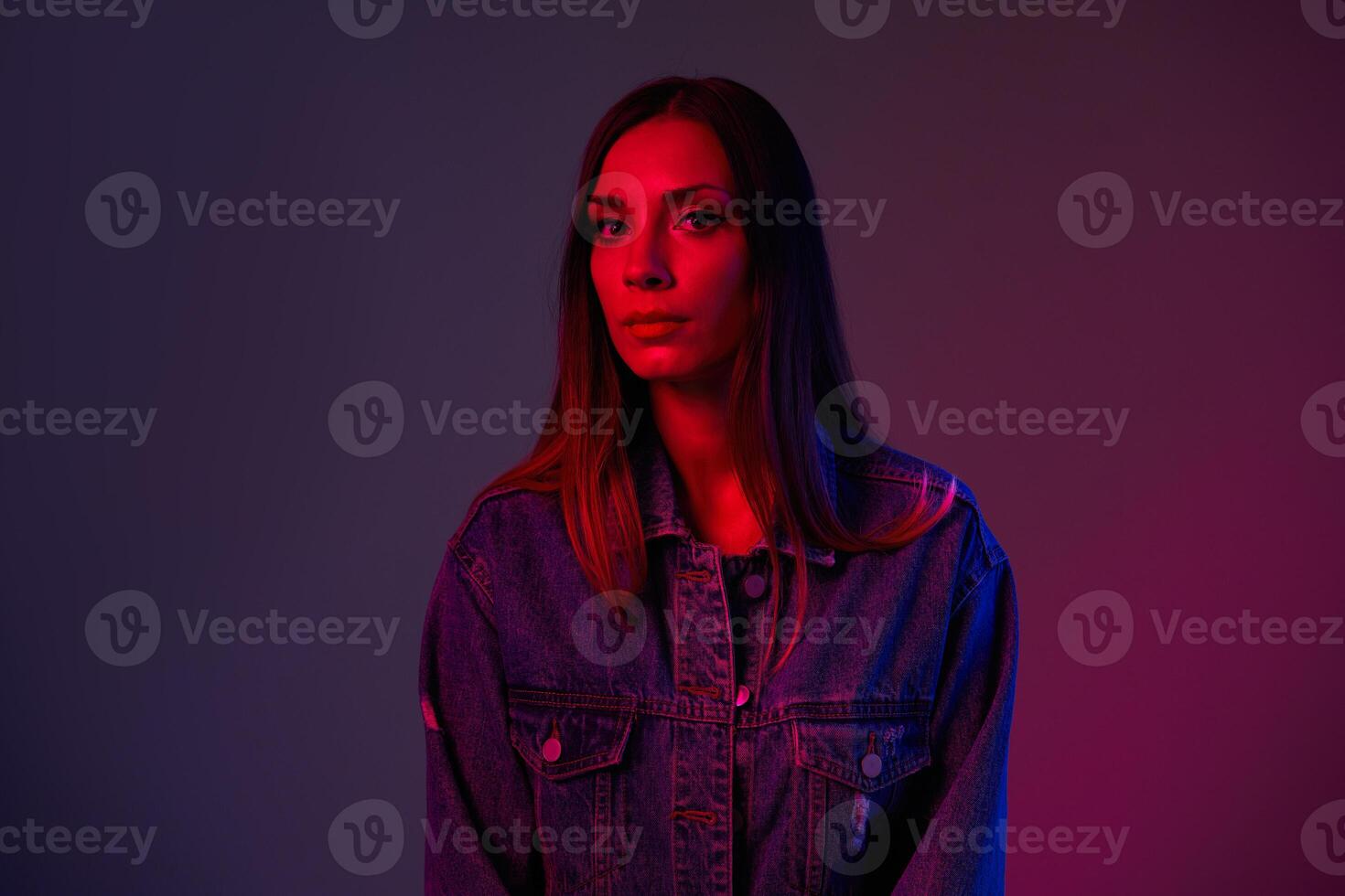 vicino ritratto di un' caucasico giovane ragazza vestito. denim giacca tiro nel studio con neon luce. foto