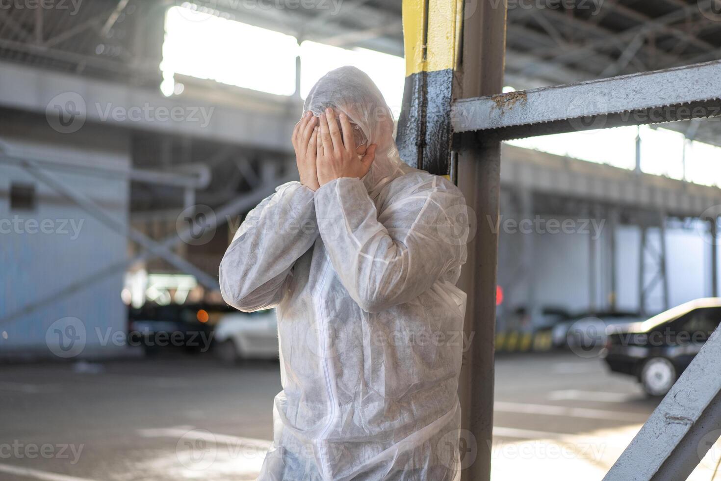 disperazione assistenza sanitaria lavoratore nel bianca covid protettivo tuta da lavoro. stanco maschio caucasico medico afferra il suo testa rannicchiarsi nel depressione durante coronavirus pandemia foto