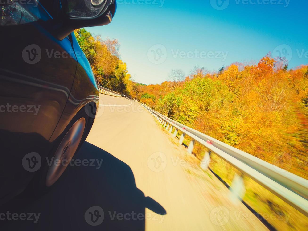 la ruota dell'auto in movimento veloce gira velocemente su strada asfaltata con alberi di natura autunnale e paesaggio su strada tortuosa. viaggio in autunno e concetto di viaggio su strada. effetto del filtro sfocatura intenzionale foto