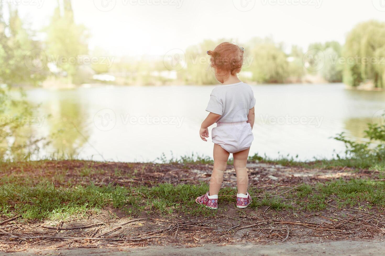 poco ragazza a piedi e giocando al di fuori vicino lago foto