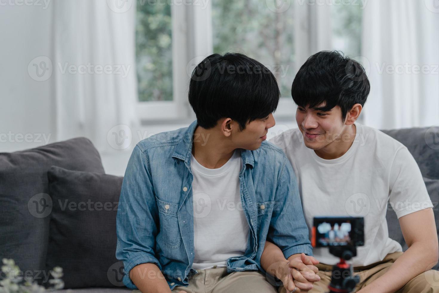 giovane coppia gay asiatica influencer coppia vlog a casa. gli uomini lgbtq coreani adolescenti si rilassano felici e si divertono usando il video del vlog della registrazione della fotocamera nei social media mentre si trovano sul divano nel soggiorno al concetto di casa. foto