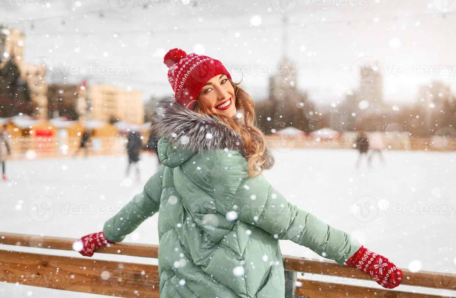 bellissimo bello di mezza età ragazza con Riccio capelli caldo inverno giacche sta ghiaccio pista sfondo cittadina quadrato. foto