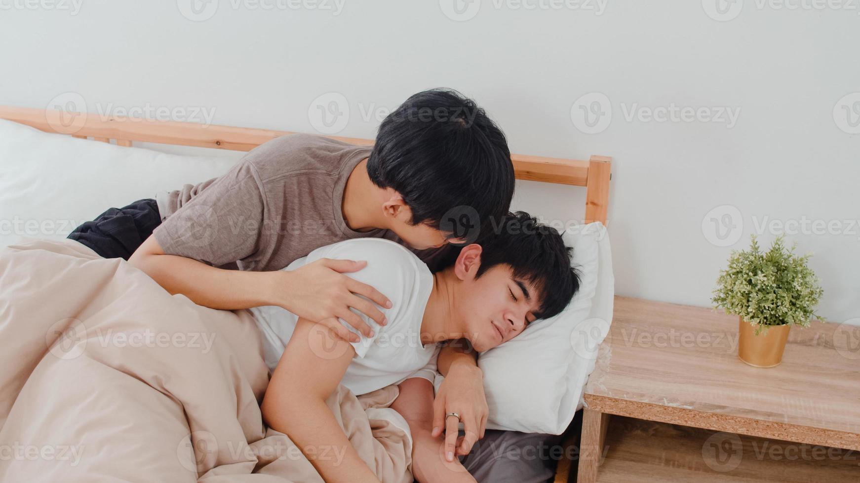 coppia gay asiatica bacio e abbraccio sul letto a casa. i giovani uomini asiatici lgbtq felici si rilassano riposano insieme trascorrono del tempo romantico dopo essersi svegliati in camera da letto a casa al mattino concetto. foto