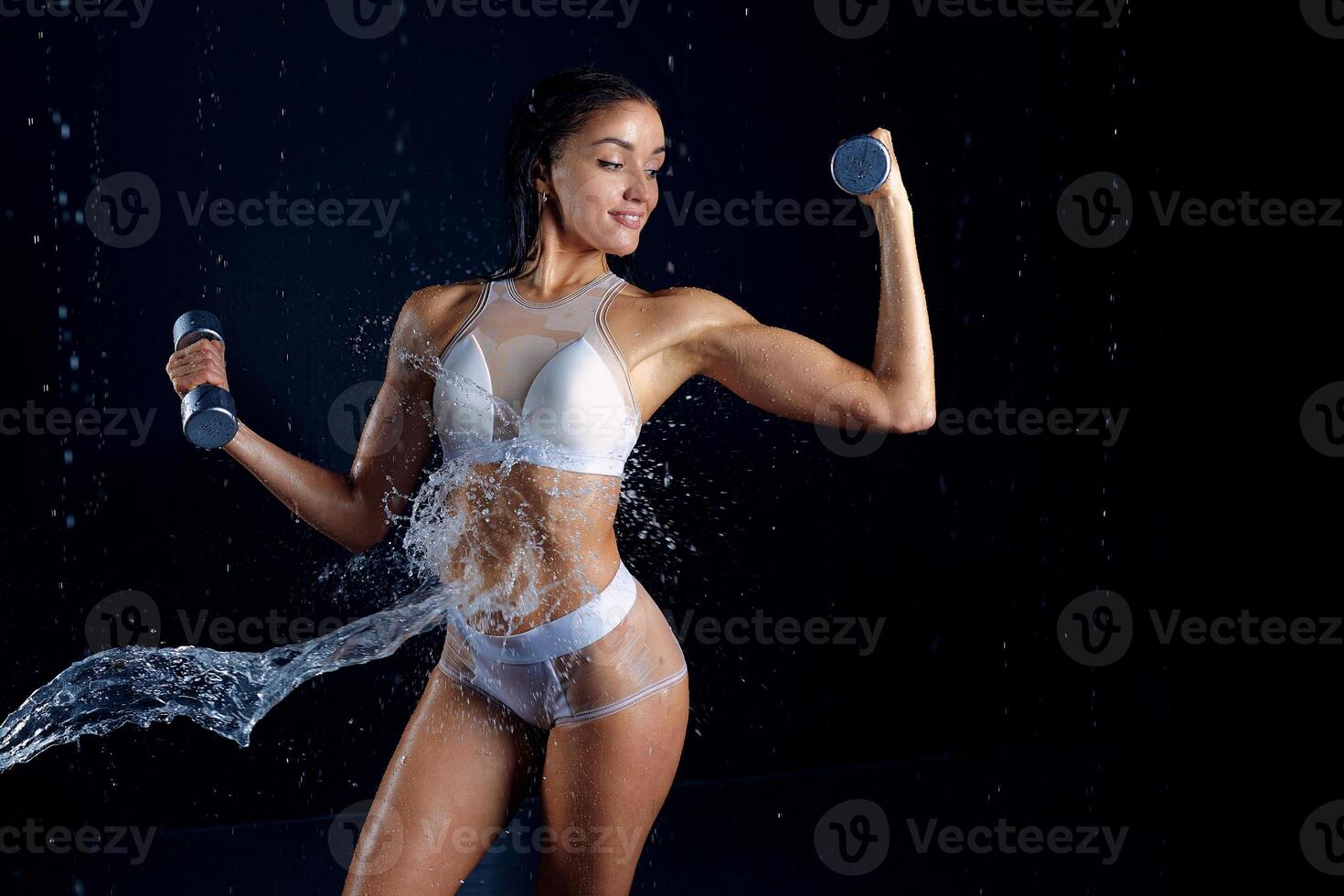 atletico donna pompaggio su muscoli con manubri foto