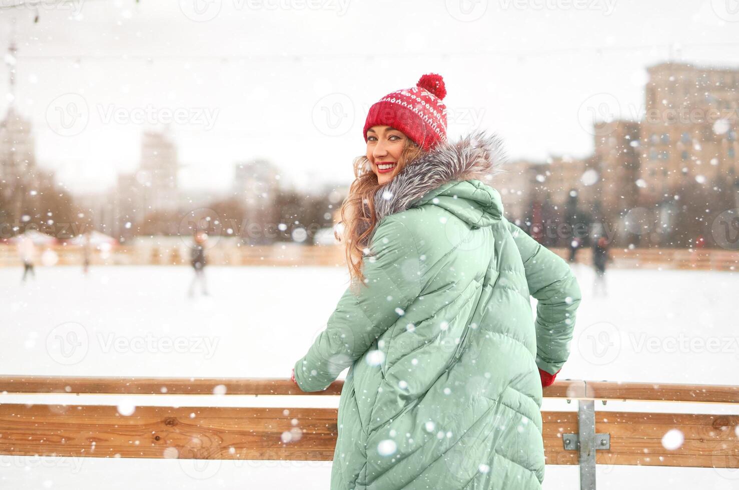 bellissimo bello di mezza età ragazza con Riccio capelli caldo inverno giacche sta ghiaccio pista sfondo cittadina quadrato. foto