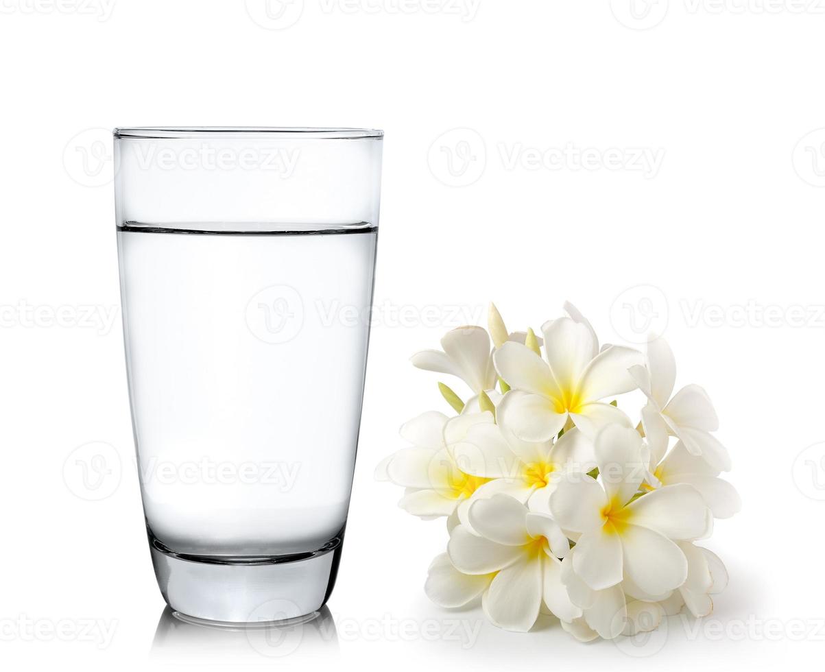 bicchiere d'acqua e fiori tropicali frangipani foto