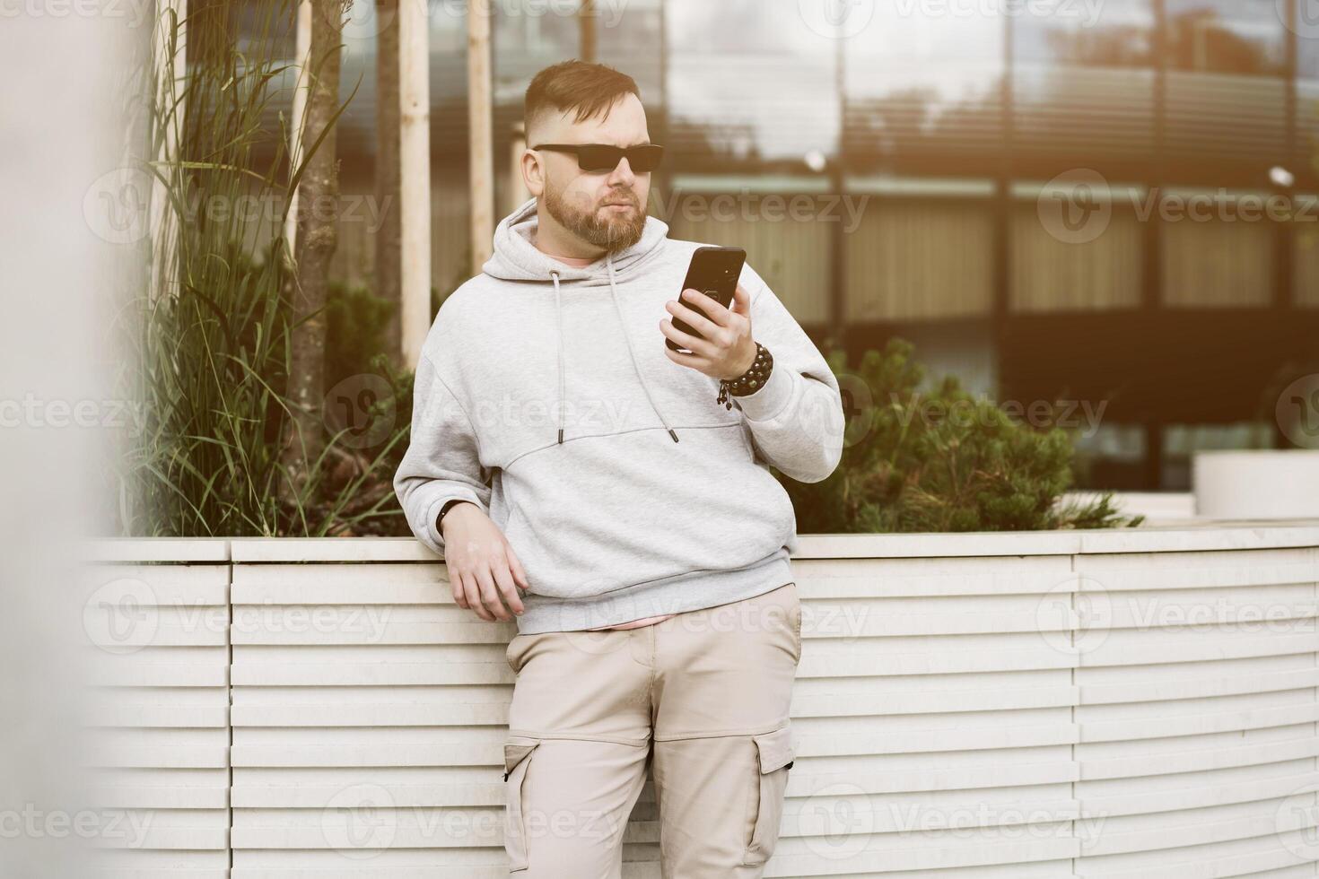 uomo nel occhiali da sole utilizzando cellula Telefono aggeggio foto