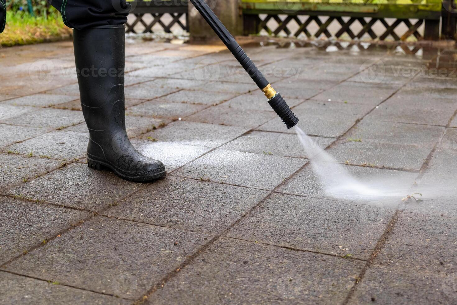 persona è utilizzando un' pressione rondella per pulito un' mattone terrazza foto