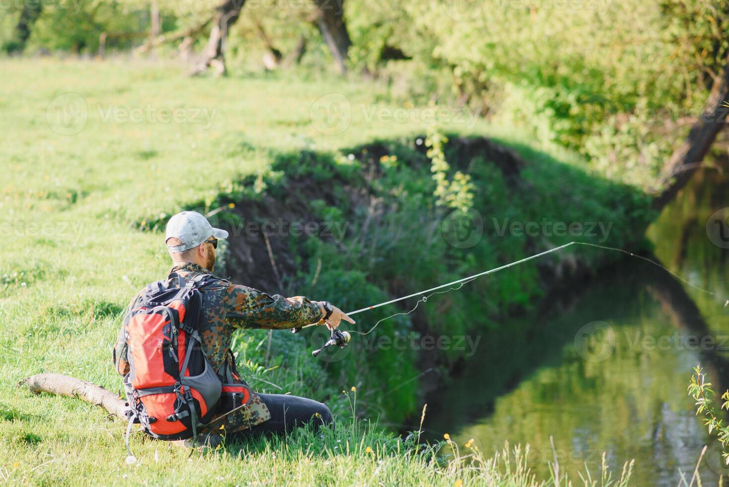 pescatore uomo pesca con Filatura asta su un' fiume banca, rotazione pesca, preda pesca foto