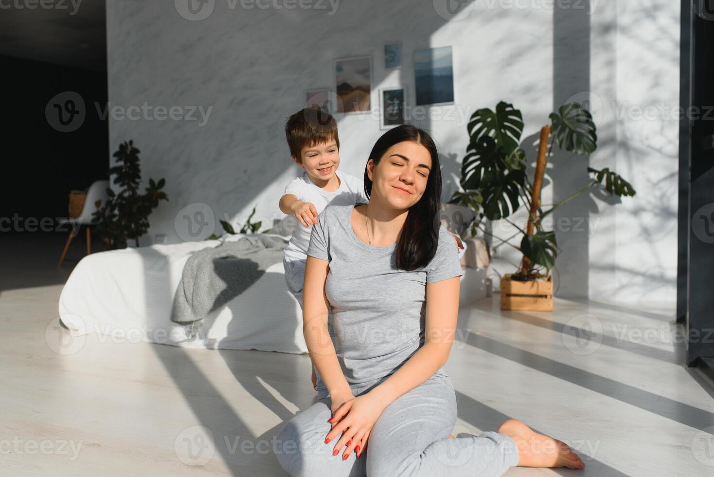 contento donna avendo divertimento con adorabile figlio nel pigiama nel Camera da letto su madri giorno. foto