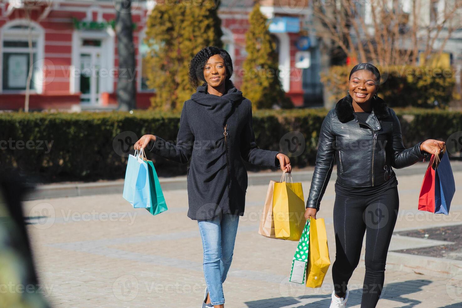 Due afro americano donne amici nel il città su un' shopping viaggio trasporto colorato shopping borse. foto