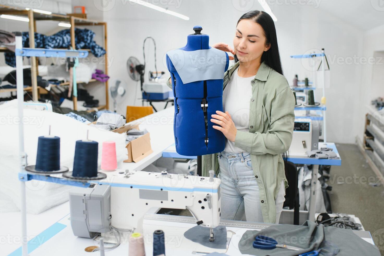 positivo giovane donna cucire con professionale macchina a officina. foto