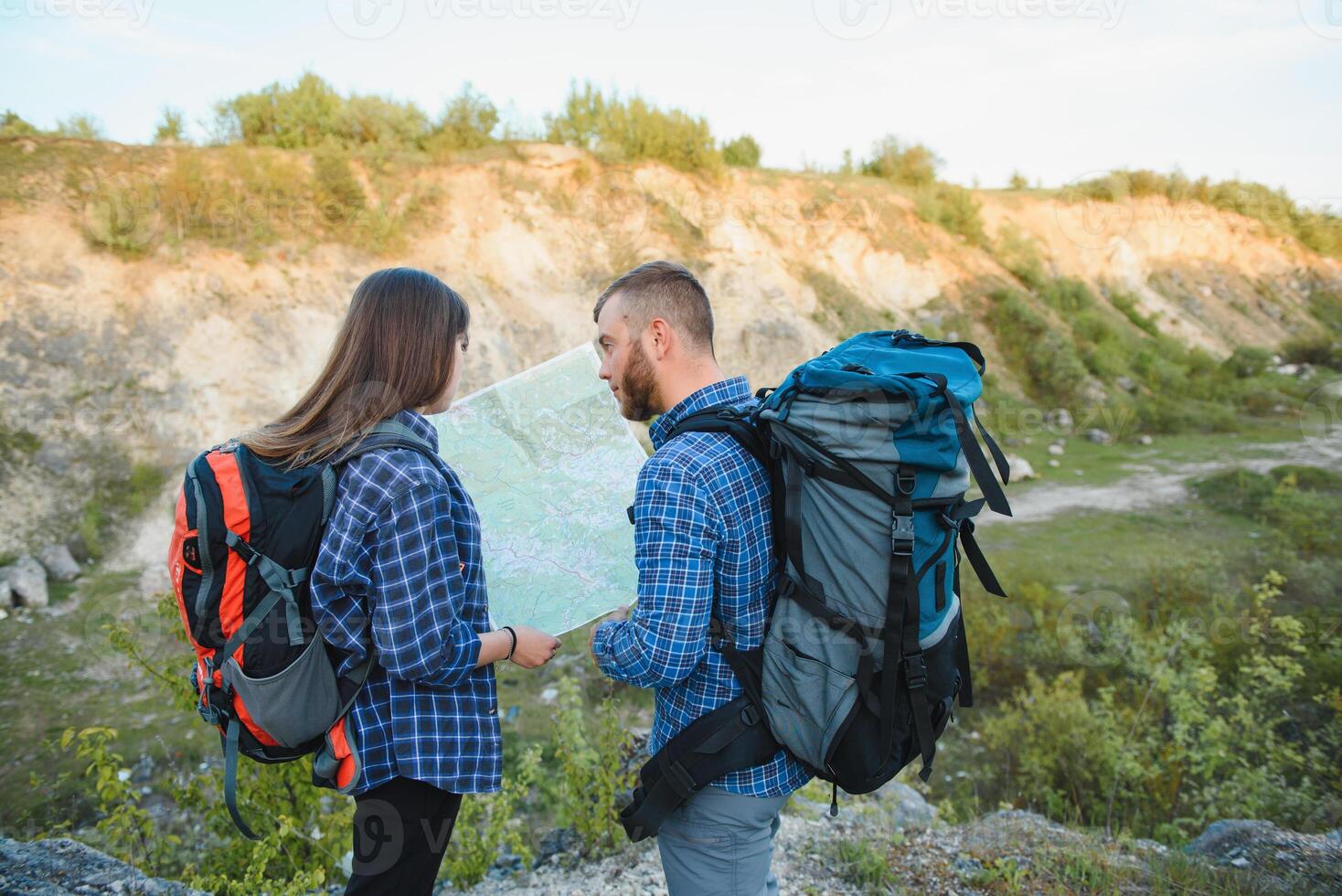 bellissimo coppia di un' i viaggiatori siamo ricerca modo su Posizione carta geografica mentre in piedi su alto collina nel soleggiato giorno, maschio e femmina escursionisti siamo a piedi insieme nel montagne durante lungo in attesa estate fine settimana foto