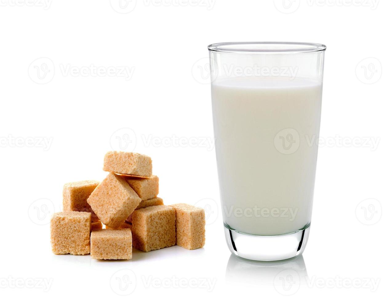 bicchiere di latte e cubetti di zucchero di canna isolati su sfondo bianco foto
