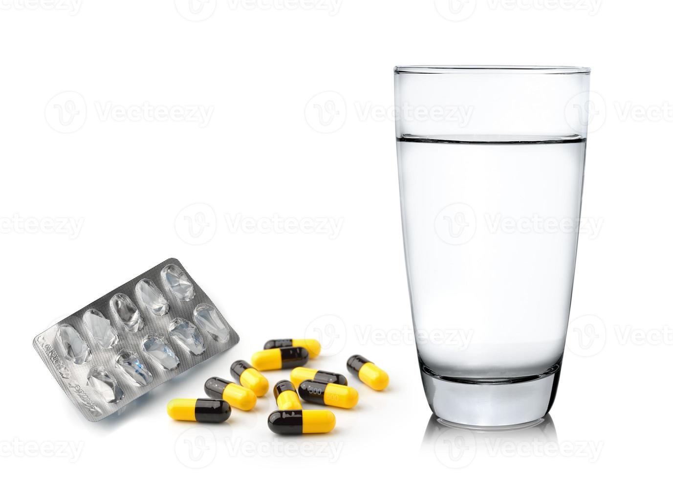 bicchiere d'acqua e pillole capsule isolate su sfondo bianco foto