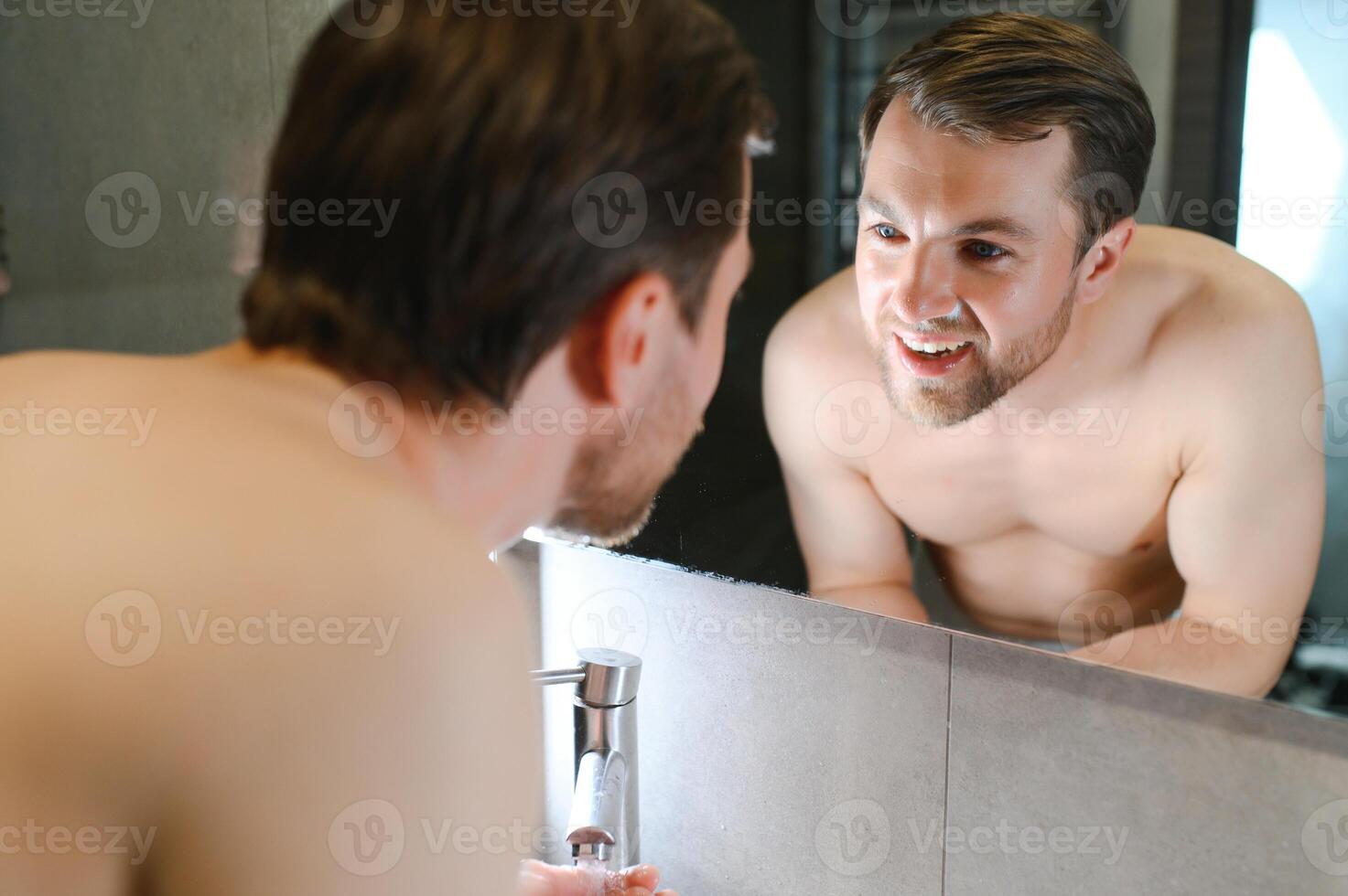 un' uomo lavaggi il suo viso dopo rasatura foto