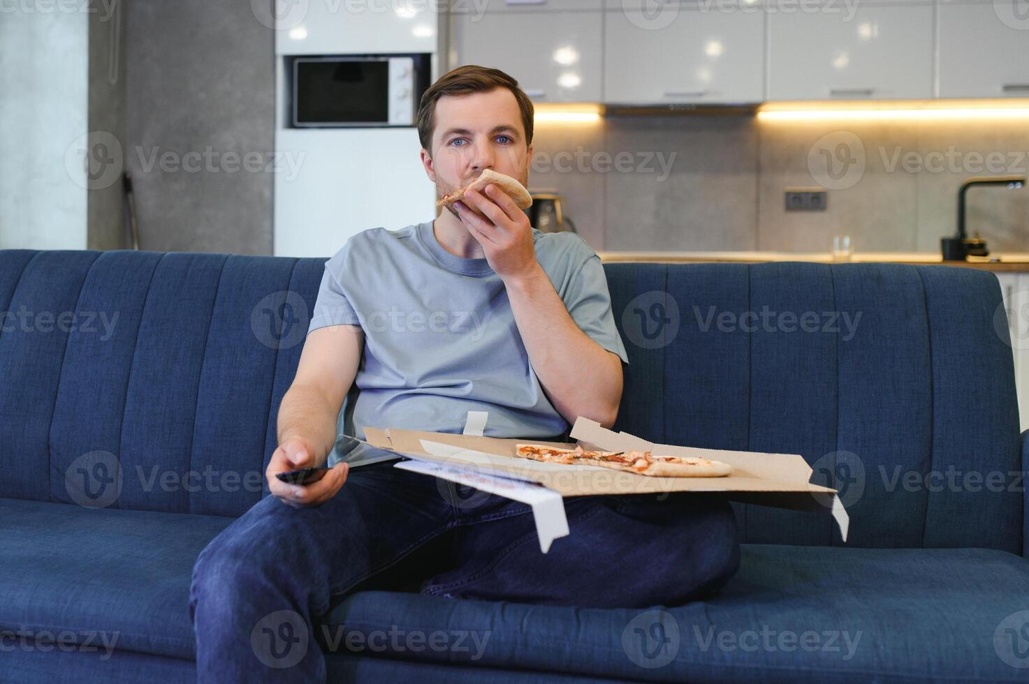 mangia Pizza mentre Guardando tv mostrare. uomo con barba al chiuso. foto