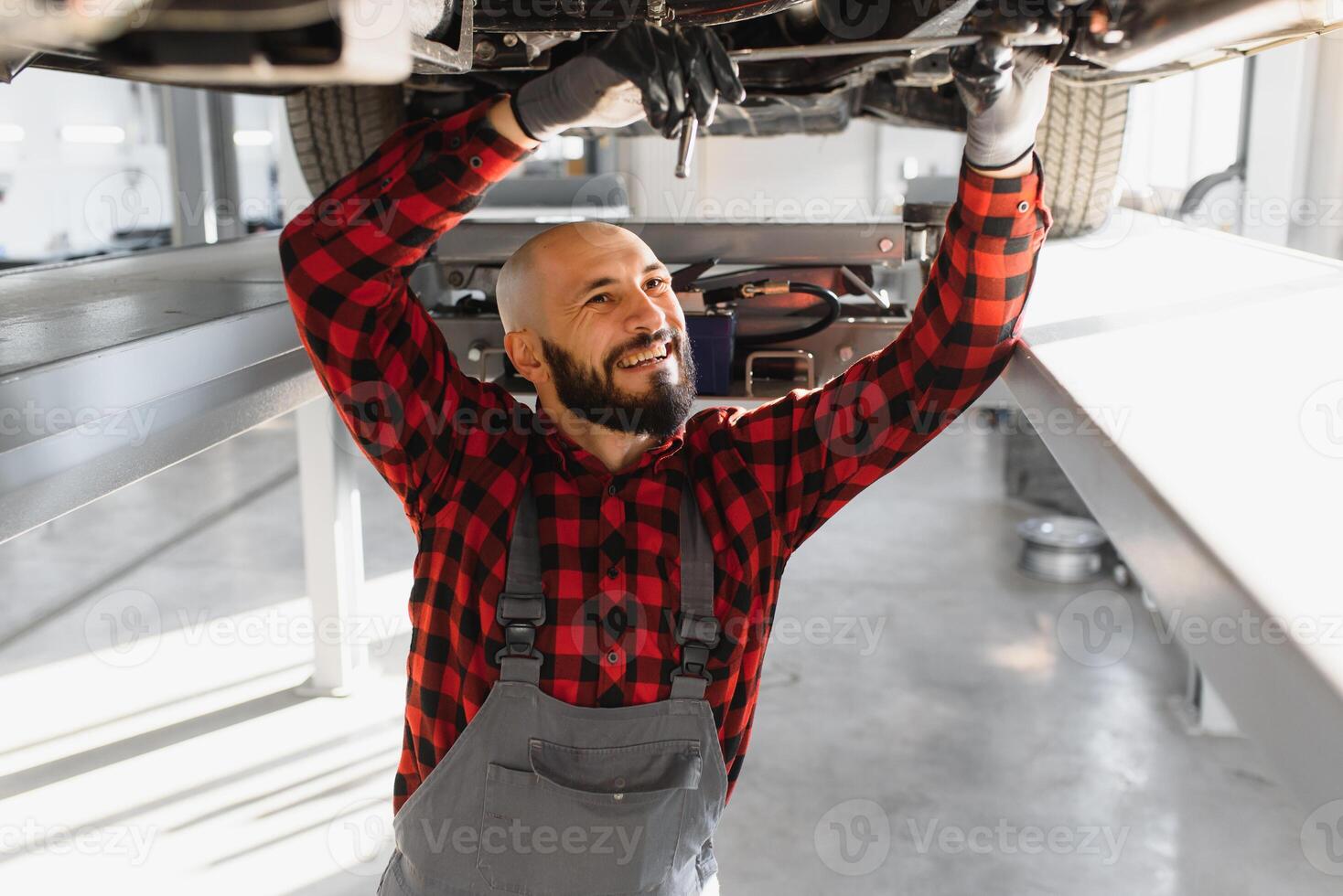 meccanico Lavorando sotto auto a il riparazione box auto. auto meccanico Lavorando nel box auto. riparazione servizio. foto