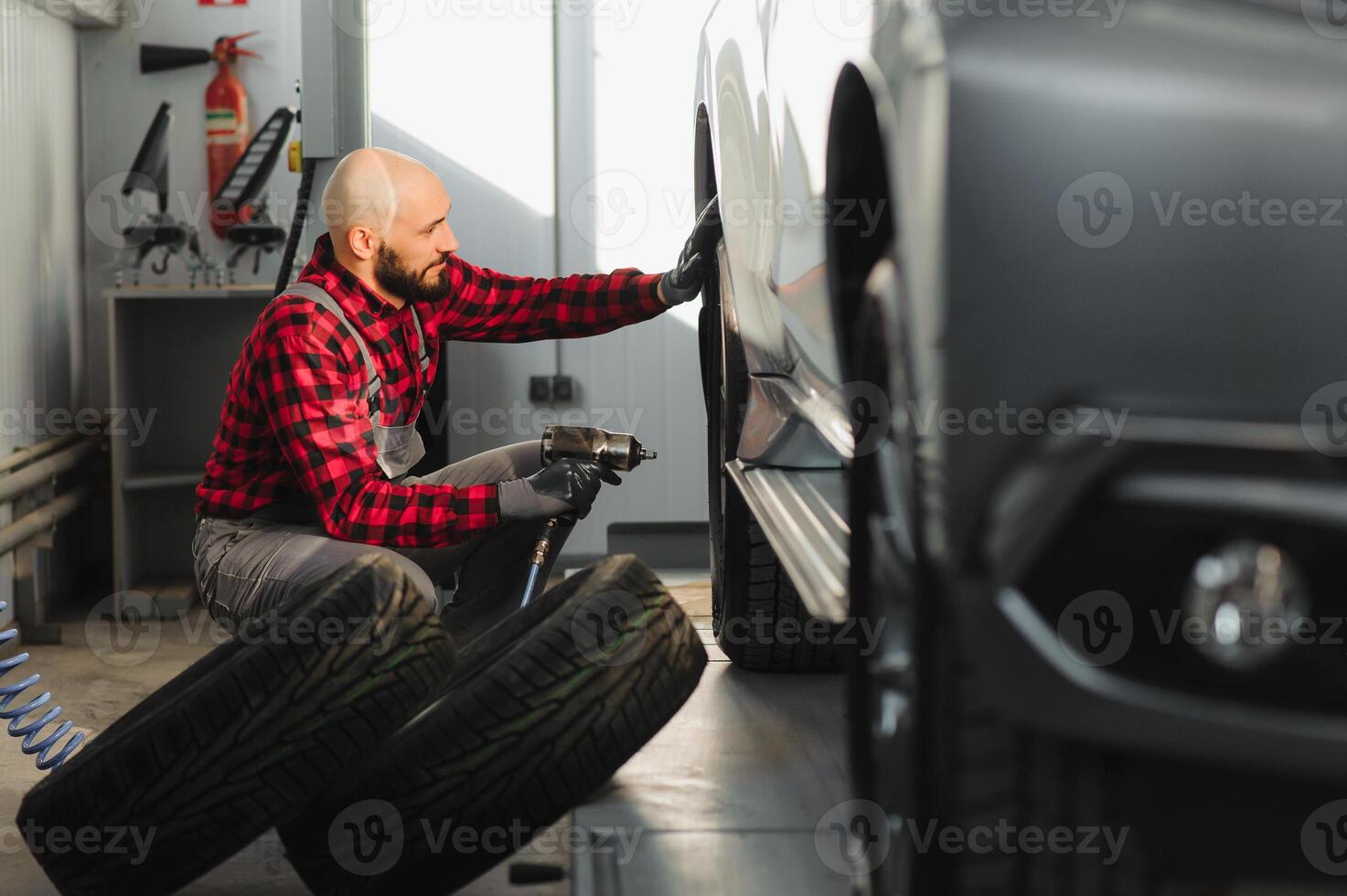 uomo riparazione un' auto ruota nel un' box auto foto