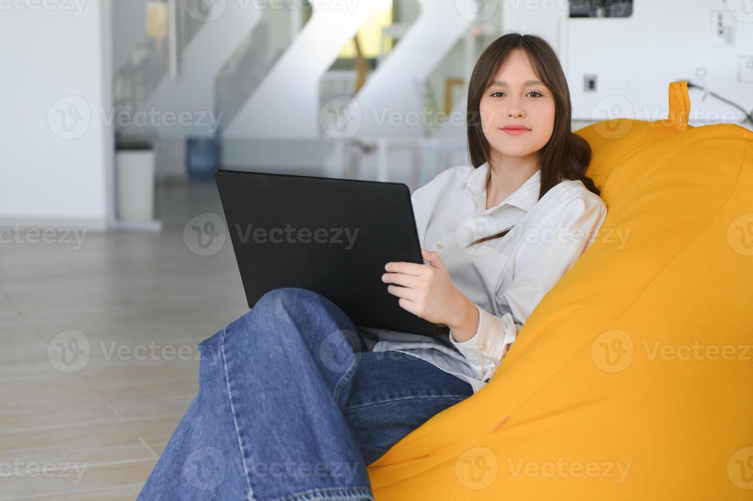 un' bellissimo caucasico femmina alunno è studiando nel Università a distanza. lei è seduta con un' il computer portatile e un' bloc notes e concentrato è Guardando un' video conferenza lezione foto