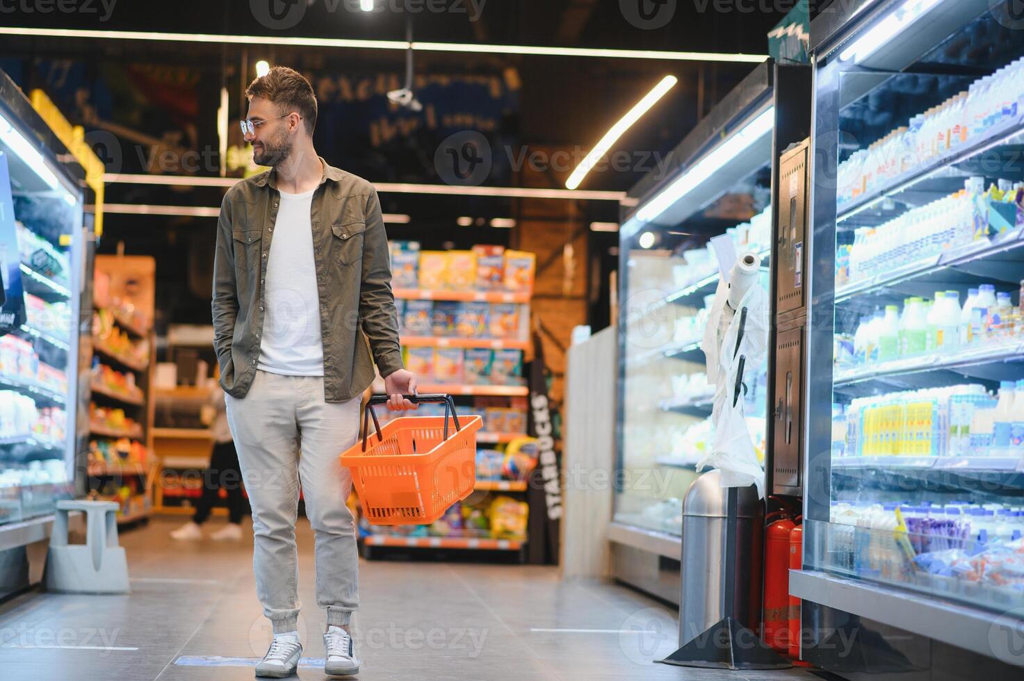 giovane uomo acquisto drogheria a il supermercato. altro i clienti nel sfondo. consumismo concetto. foto