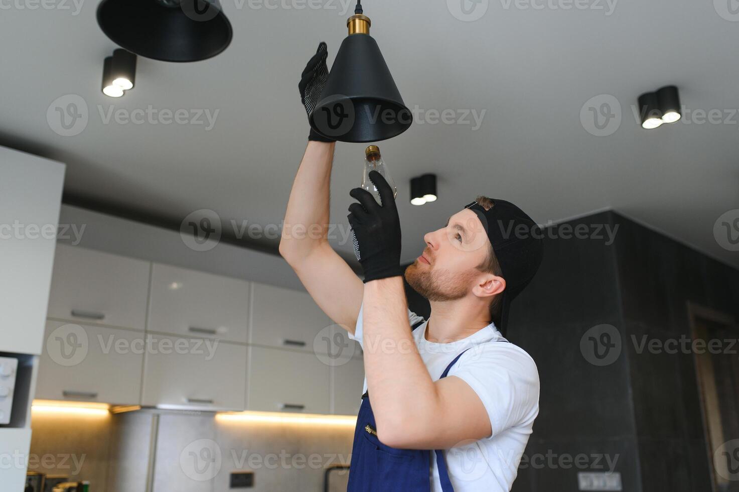 un' maschio elettricista i cambiamenti il leggero bulbi nel il soffitto luce. Uomini domestico doveri. cura di elettrico elettrodomestici a casa foto