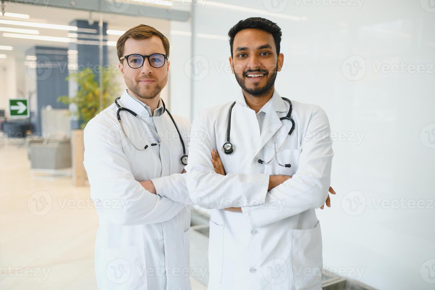 un indiano medico e un' europeo medico In piedi insieme nel un' ospedale atrio. foto