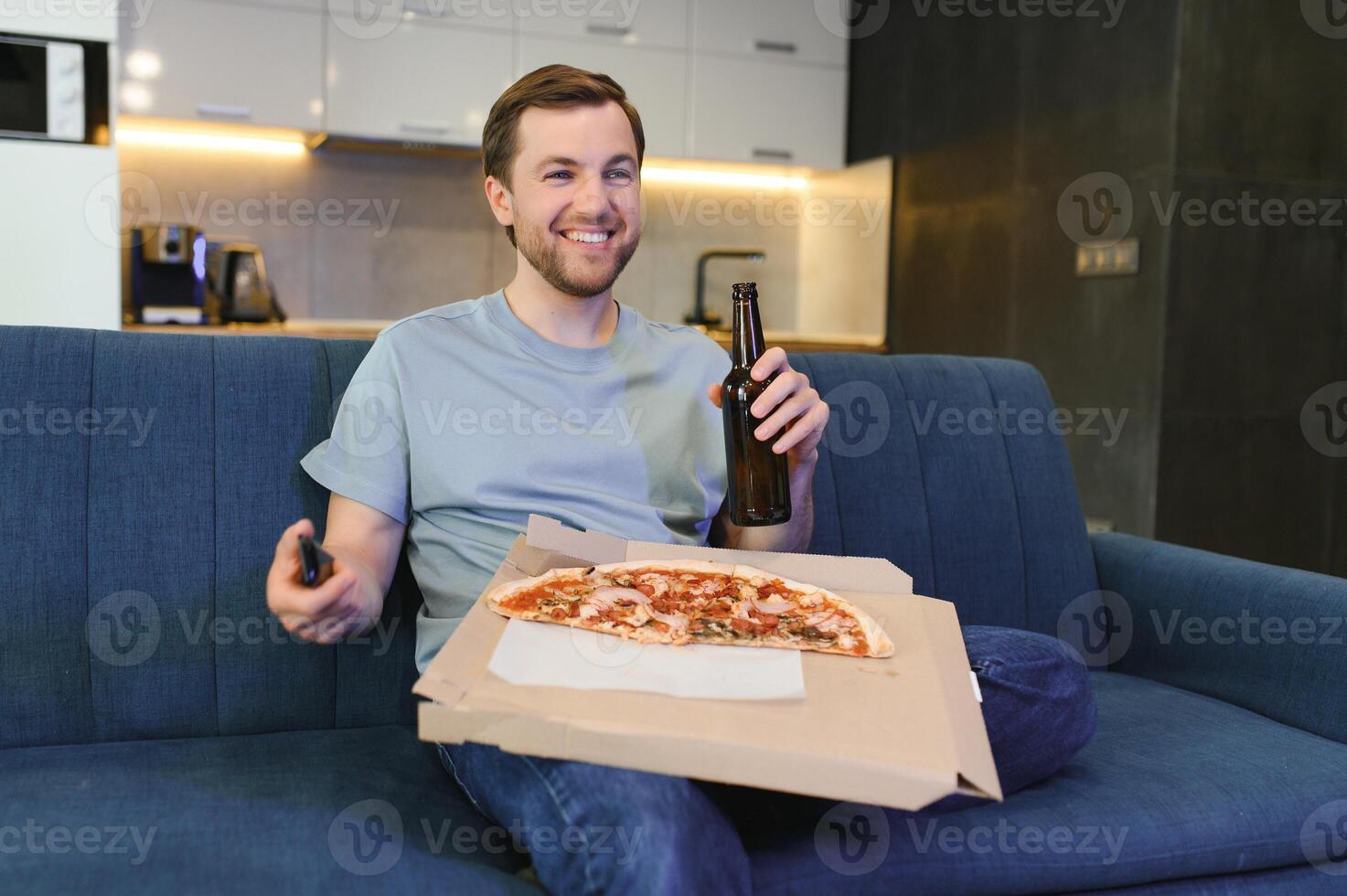 mangia Pizza mentre Guardando tv mostrare. uomo con barba al chiuso. foto